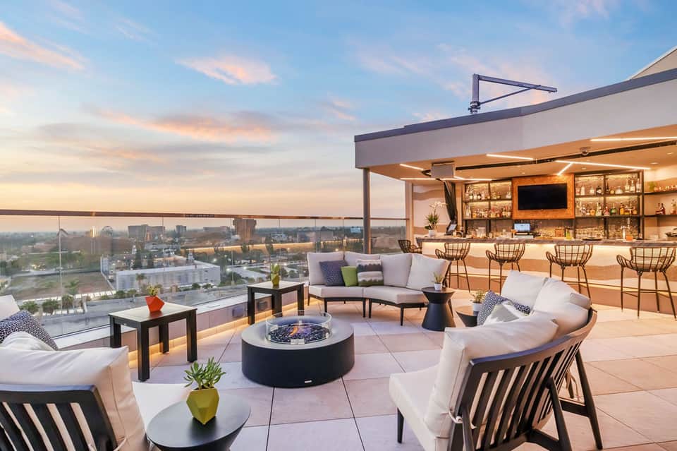 Rooftop bar and lounge at dusk with city skyline views and modern seating