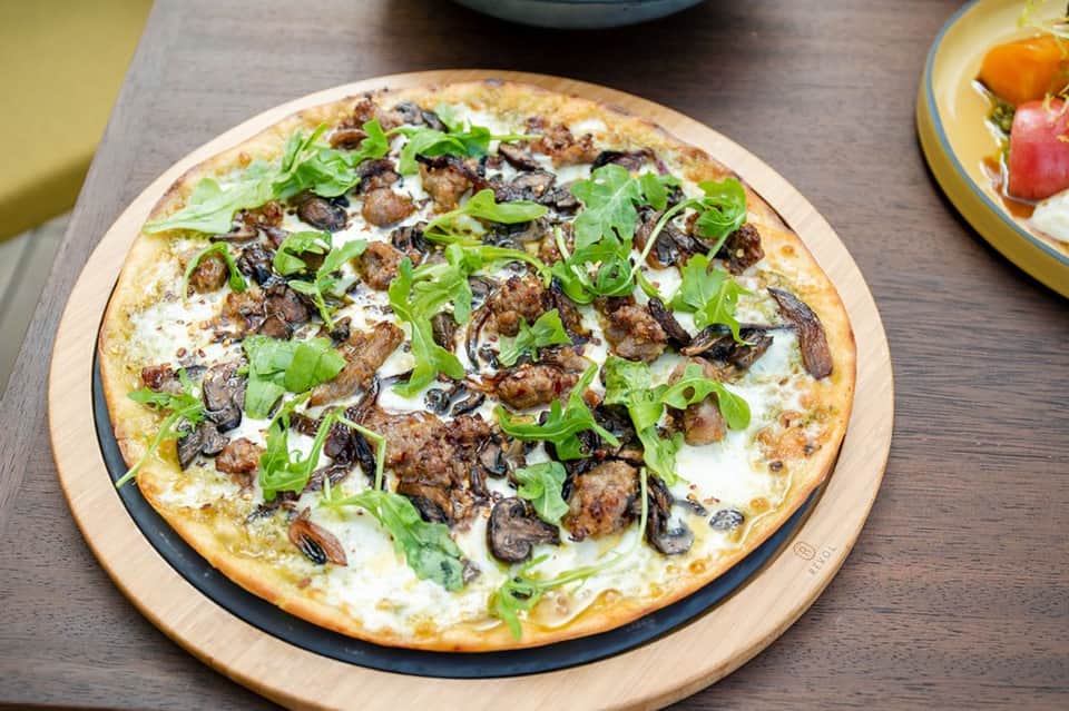 Gourmet pizza topped with ground beef, mushrooms, and fresh green onions on a wooden serving board