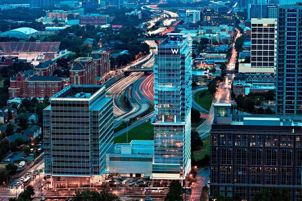 Aerial night view of modern hotel with W sign, curved architecture, and illuminated city streets