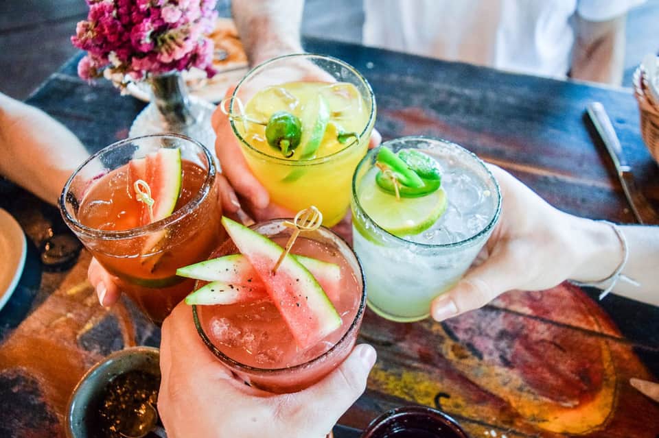 Colorful tropical cocktails with fresh fruit garnishes on beachside table