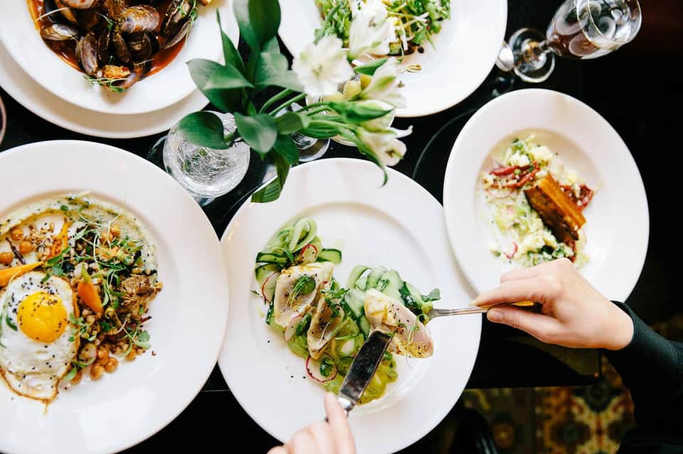 Fine dining overhead view with plated seafood dishes, fresh herbs, and wine glasses