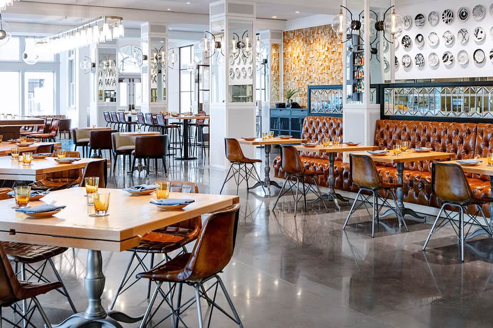 Modern restaurant interior with orange leather booths, white tables, and decorative plates