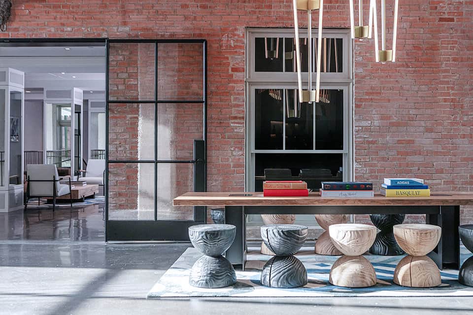 Exposed brick industrial space with wooden display table and sculptural wooden stools