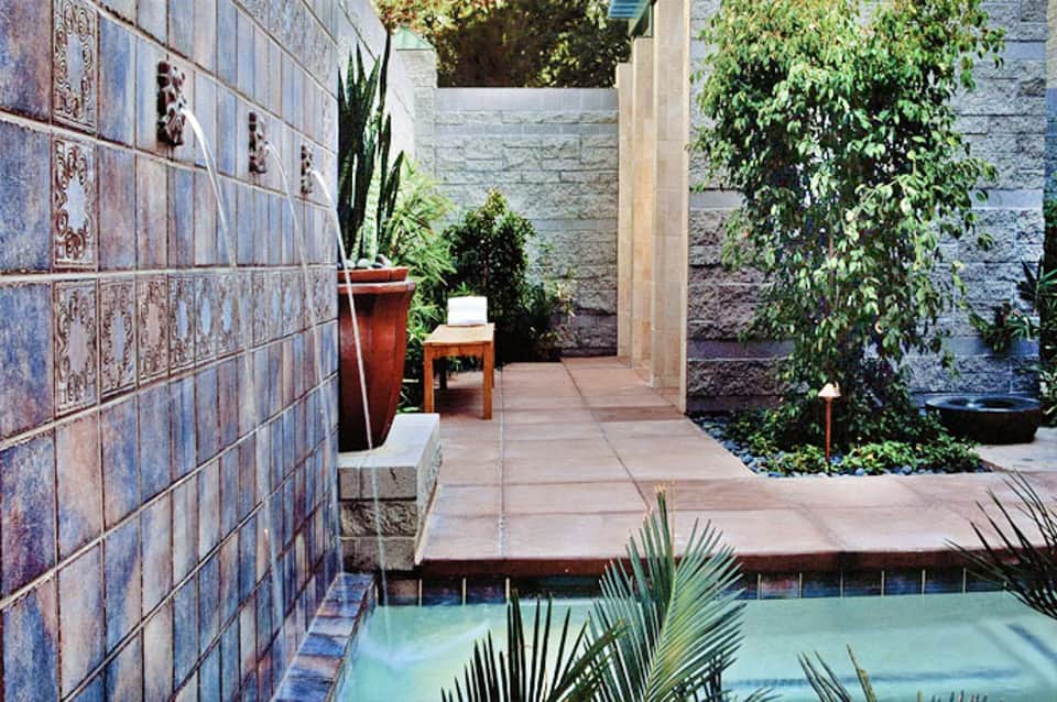 Modern courtyard pool with decorative blue tile walls and lush greenery