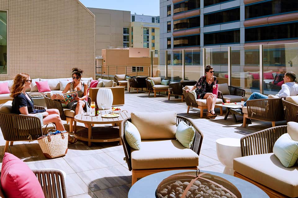 Rooftop terrace with lounge seating, colorful pillows, fire pit, and city views