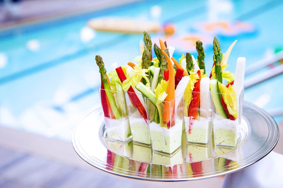 Elegant appetizer platter with asparagus and colorful vegetable skewers by pool