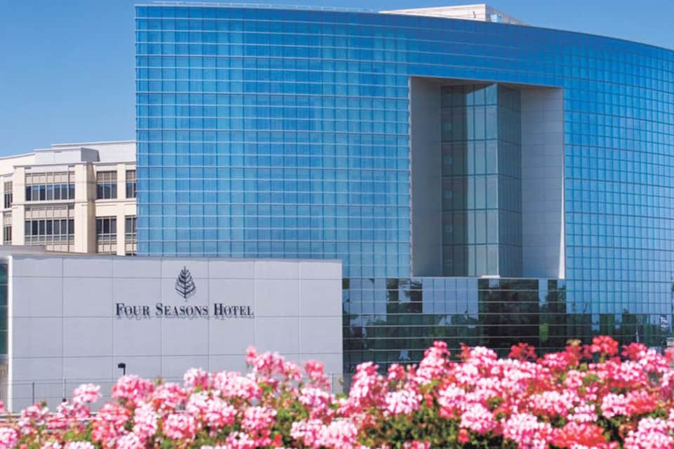 Four Seasons Hotel modern blue glass building with pink flowers and clear sky