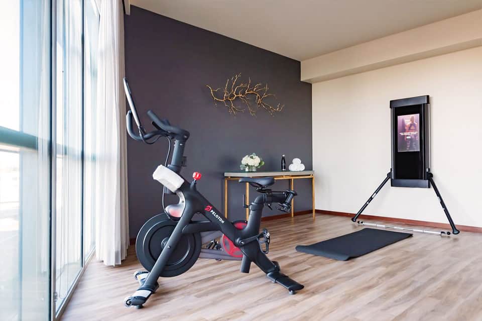 Modern fitness room with stationary bike, dark accent wall, and interactive display screen