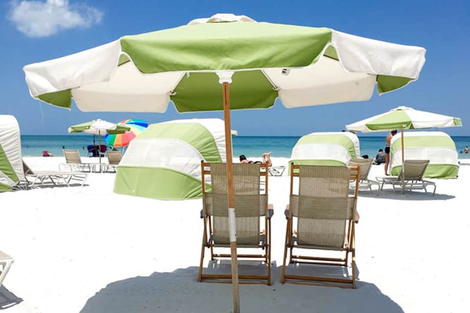 Beach umbrellas and lounge chairs with ocean view under bright blue sky