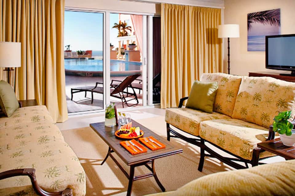Luxury cruise ship cabin with golden curtains, patterned sofas, and ocean view from private balcony