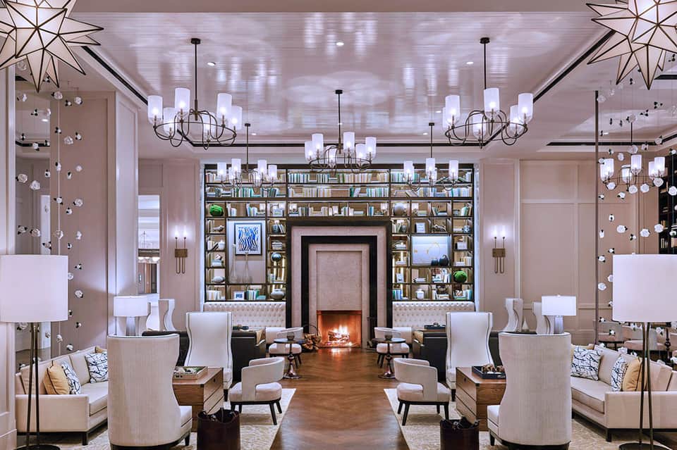 Luxury lounge with symmetrical seating, fireplace, built-in bookshelves, and hanging crystal chandeliers