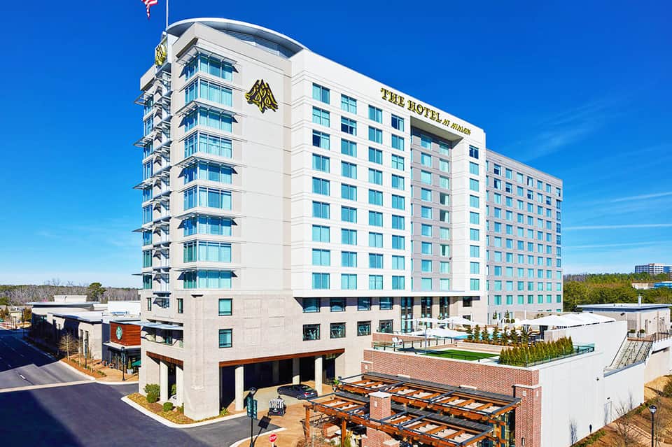 Modern white hotel building with curved balconies under clear blue sky