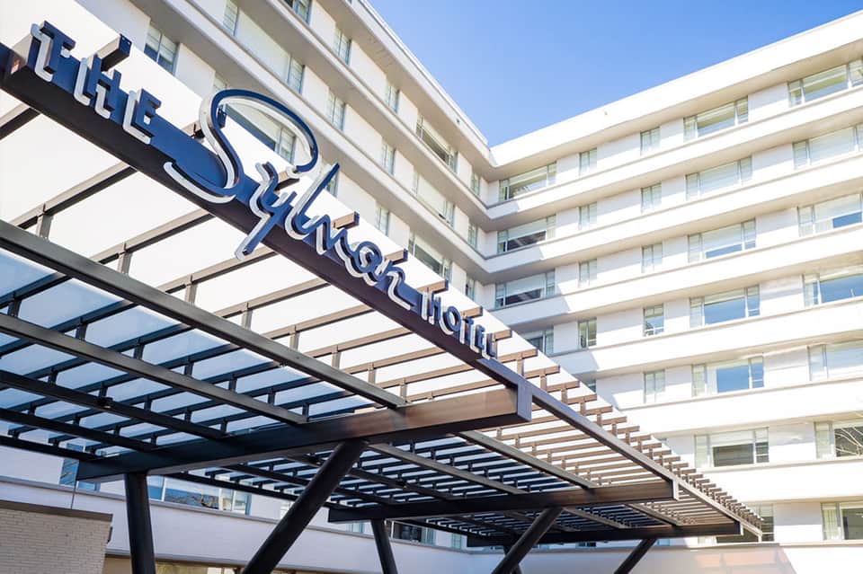 Modern hotel entrance with blue neon sign and contemporary architecture under clear sky