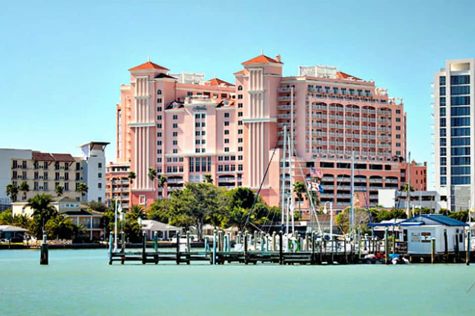 Pink waterfront hotel with docking area viewed from turquoise water