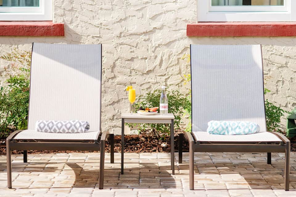 Two modern lounge chairs with textured fabric facing a brick building on a patio
