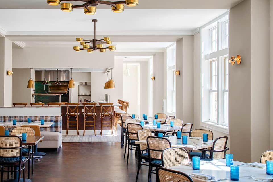 Elegant dining room with rattan chairs, pendant lights, and a central bar area