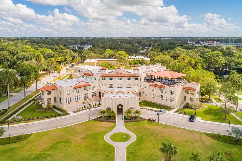Aerial view of Spanish colonial-style resort with terra cotta roofs surrounded by palm trees and manicured grounds