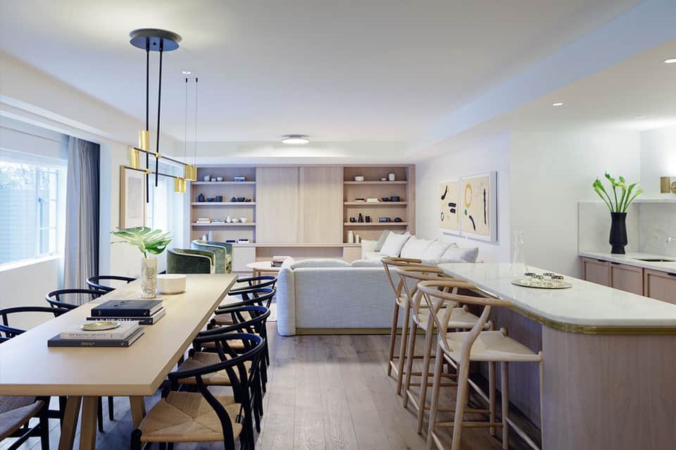 Modern open-concept living space with dining table, kitchen bar, sofa, and built-in shelving