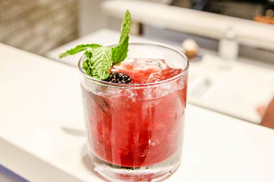 Craft cocktail with fresh mint and berries in an upscale indoor setting