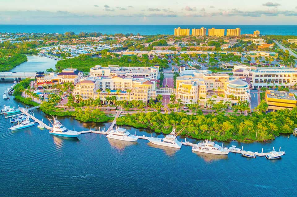 Aerial view of waterfront resort with yellow buildings, boats, and turquoise water