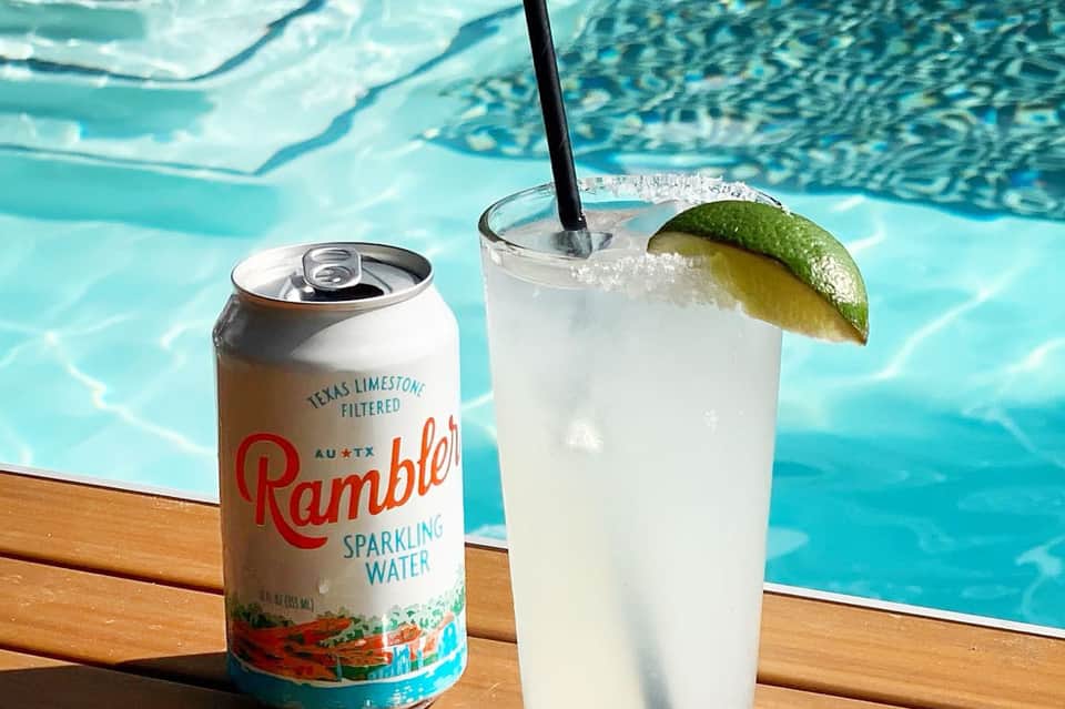 Rambler sparkling water and cocktail with lime garnish at pool's edge