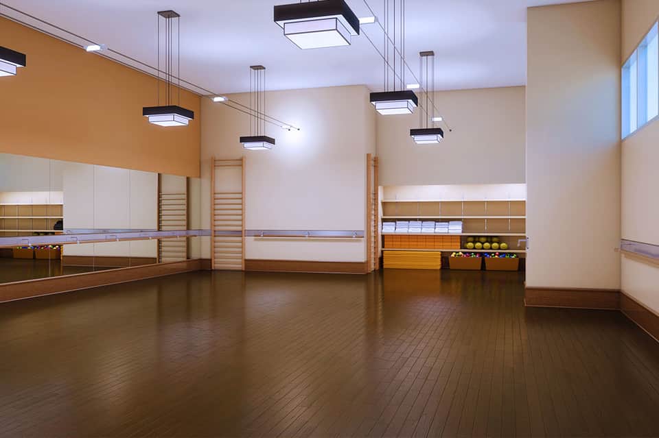 Spacious dance studio with wooden floors, mirrors, and ballet barres along walls