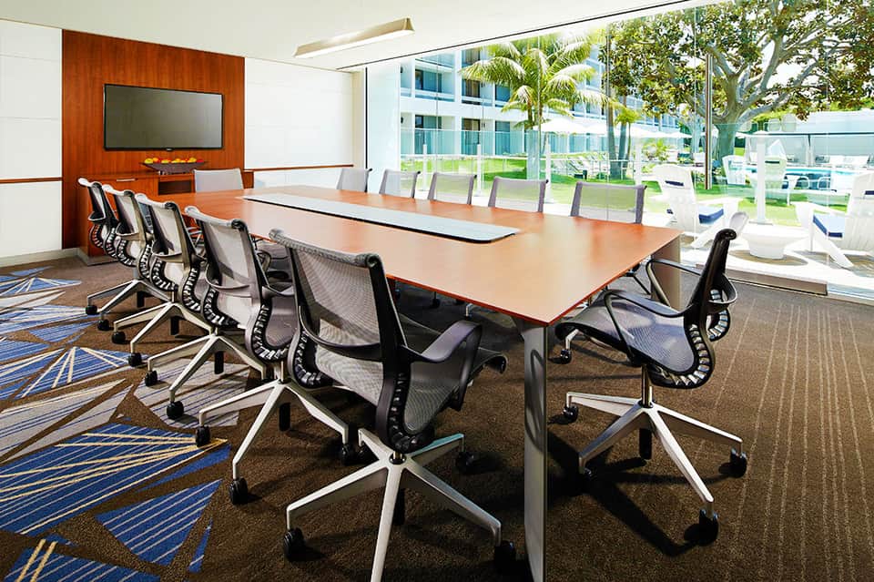 Modern conference room with long wooden table, mesh chairs, and panoramic views
