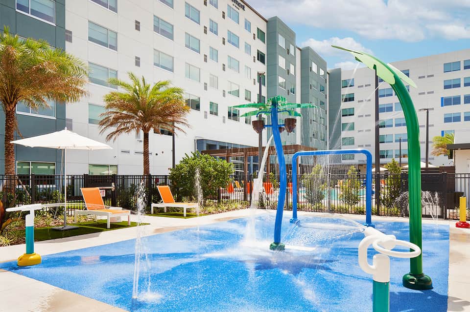 Colorful splash pad with water features and interactive play equipment in courtyard