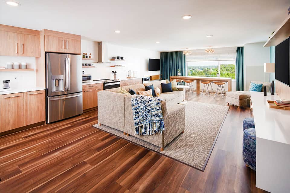 Modern open-concept suite with light wood cabinetry, stainless steel appliances, and ocean view windows