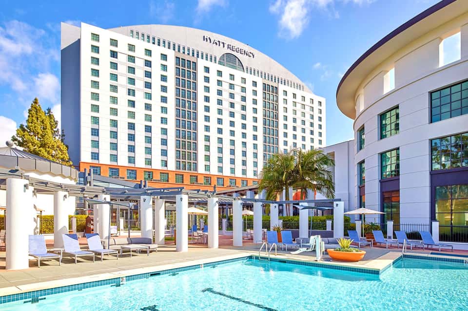 Hyatt Regency hotel pool area with lounge chairs, umbrellas, and modern white buildings