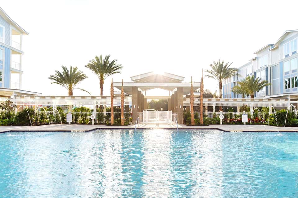 Resort pool with modern pergola structures, palm trees, and white railings