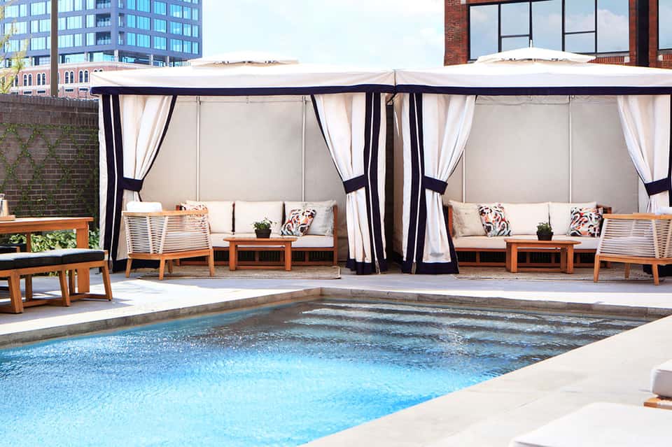 Rooftop pool lounge with black and white cabanas and cushioned seating