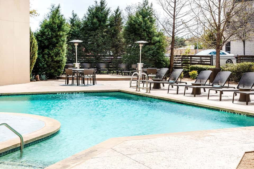Resort swimming pool with clear turquoise water and lounge chairs in sunny courtyard