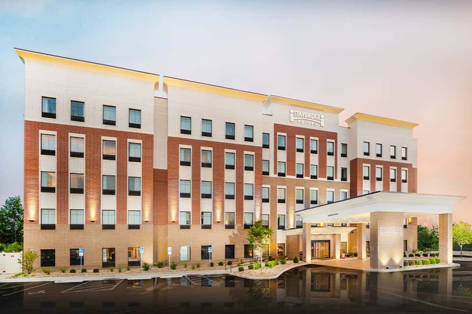 Staybridge Suites hotel exterior at dusk with brick and stone facade and entrance portico