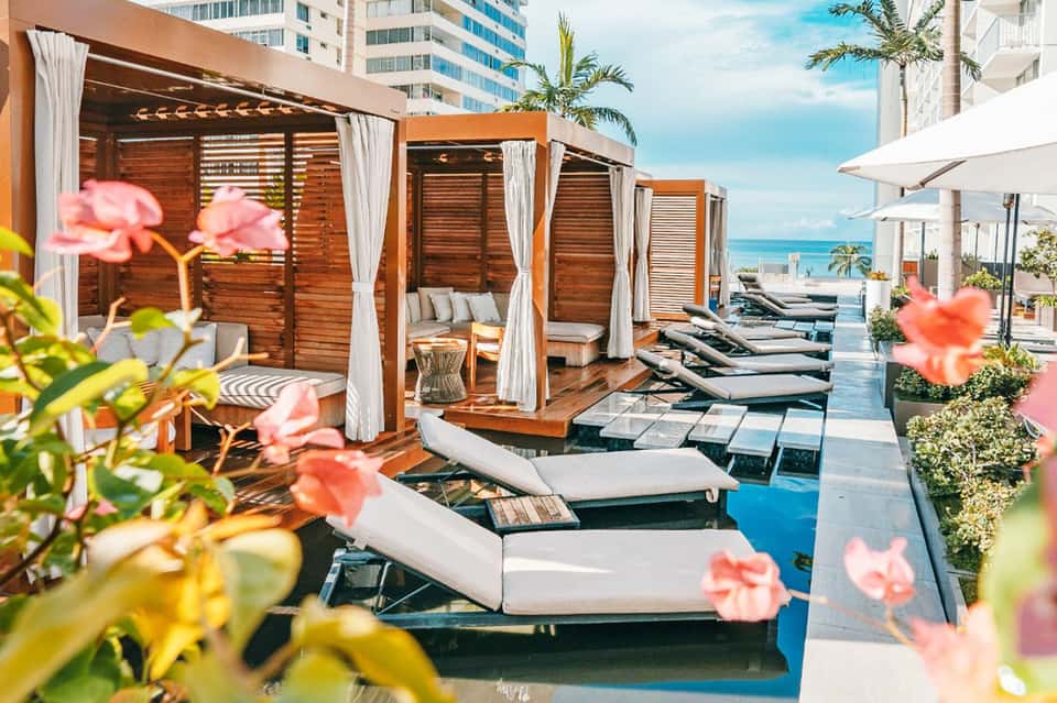 Luxury beachfront resort with wooden cabanas, loungers, ocean views, and palm trees