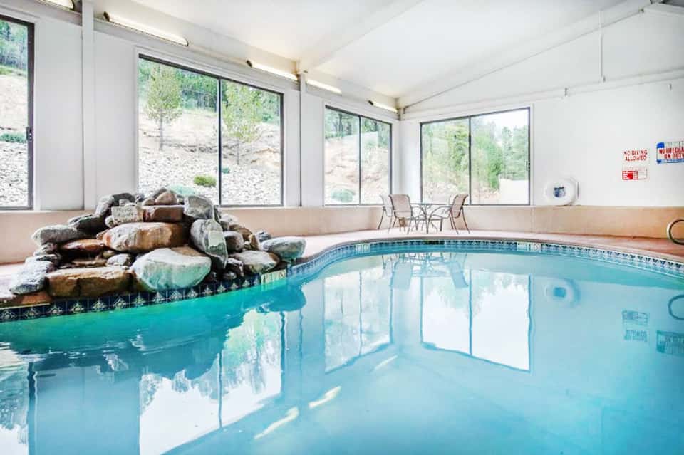 Indoor pool facility with rock waterfall feature and large windows