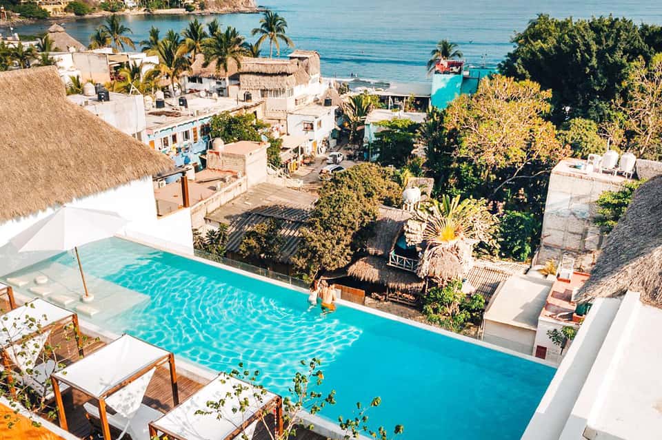 Luxury cliffside resort with turquoise infinity pool, white buildings, and ocean views