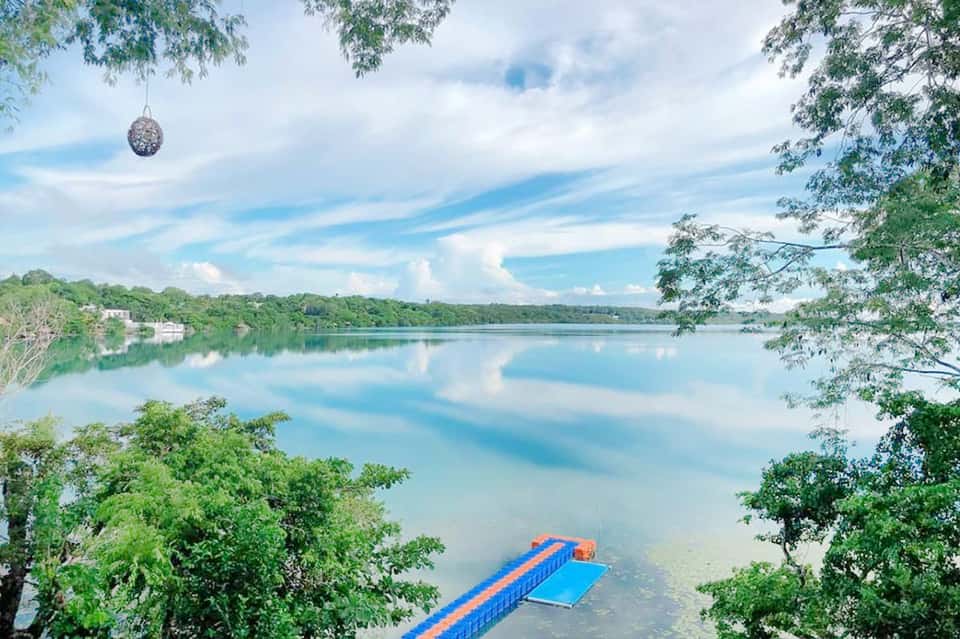 Serene lake with blue floating dock platform surrounded by lush green forest and mountains