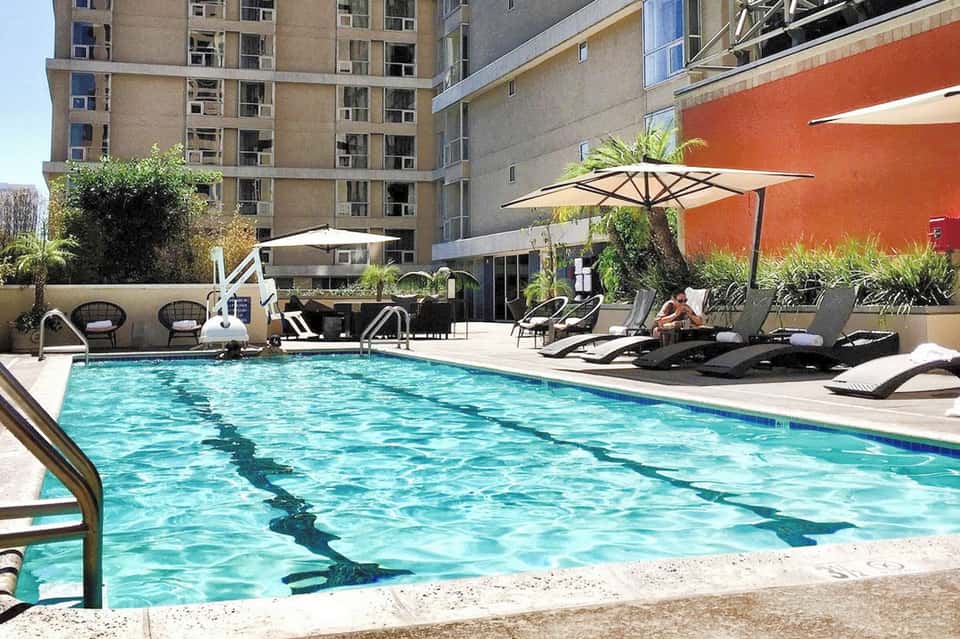 Contemporary urban hotel pool with dark lounge chairs and orange accent wall