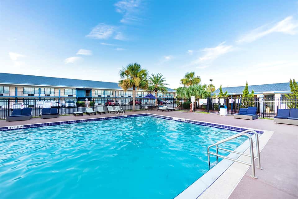 Rectangular outdoor swimming pool with palm trees and hotel buildings