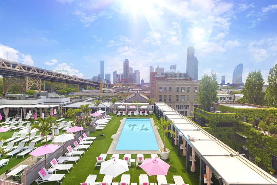 Rooftop pool and lounge area with pink umbrellas overlooking Chicago skyline and bridge
