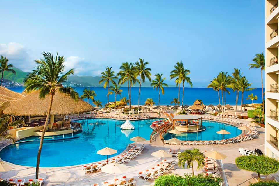 Luxurious resort pool with palm trees, blue water, and ocean view