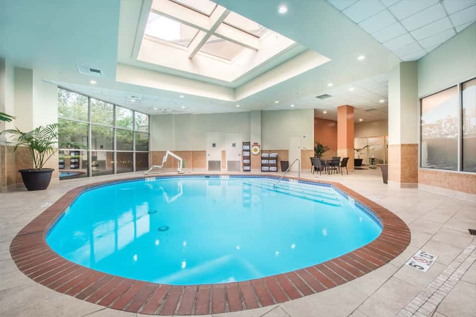 Indoor heated pool with brick surround, skylights, and modern lounge area