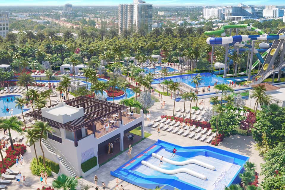 Aerial view of resort with water park, pools, slides, palm trees, and city skyline