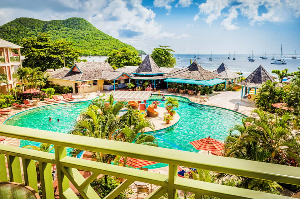 Vibrant tropical resort pool with volcano-shaped features and ocean view backdrop