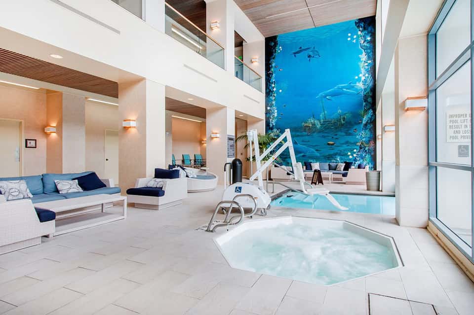 Modern indoor aquatic center with spa tub, pool, and large underwater mural