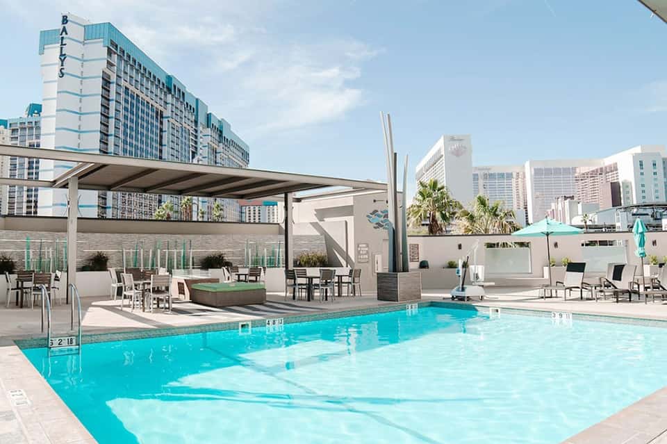 Modern resort pool with turquoise water, lounge chairs, and high-rise hotels in background