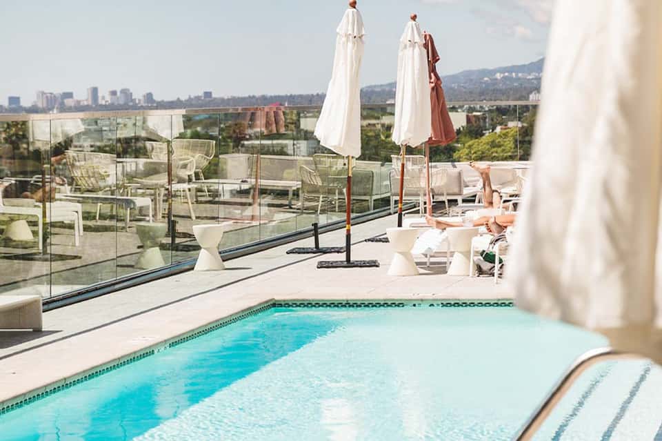 Rooftop pool with panoramic city views, white umbrellas, and lounge seating