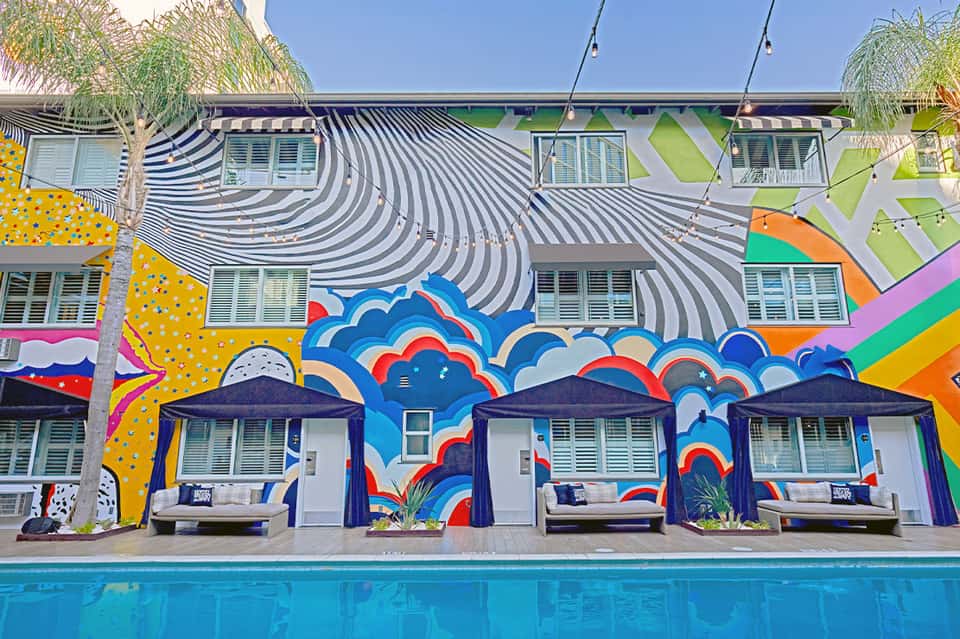 Colorful poolside cabanas with vibrant murals and striped beach umbrellas