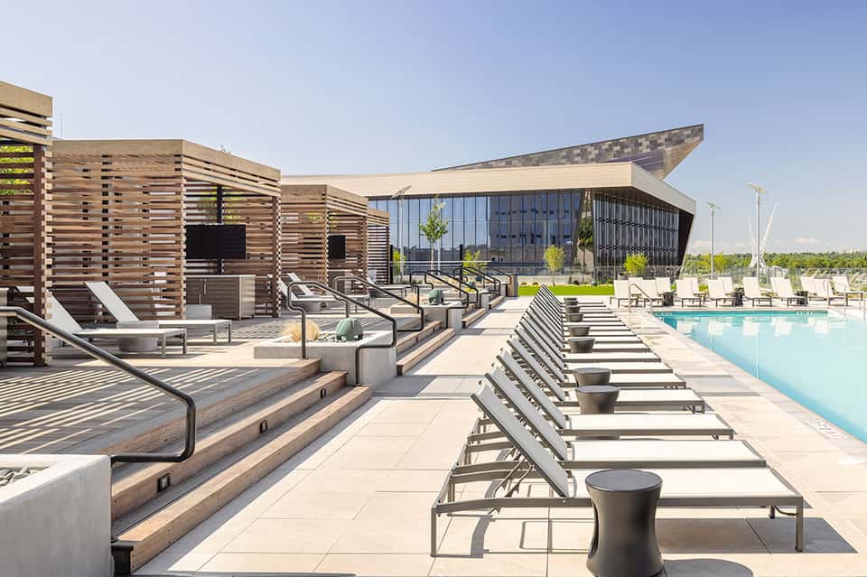 Modern poolside lounge with wooden pergolas, loungers, and glass building